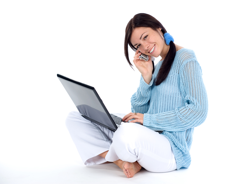 dziewczyna rozmawiająca przez telefon i pracująca przy komputerze